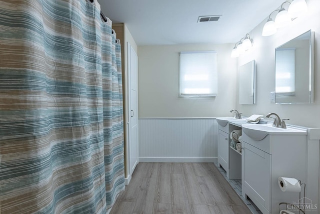 989 E Ogden Rd, Adams Twp, OH 45177 - full bathroom featuring wood finished floors, a wainscoted wall, and two vanities