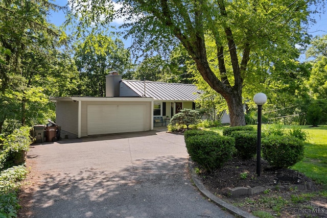 281 Compton Rd, Wyoming, OH 45215 - mid-century modern home featuring a chimney, a garage, concrete driveway, a metal roof, and a standing seam roof