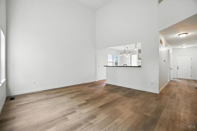2380 Oaktree Pl, Cincinnati, OH 45238 - unfurnished living room featuring hardwood / wood-style floors, a chandelier, and a high ceiling