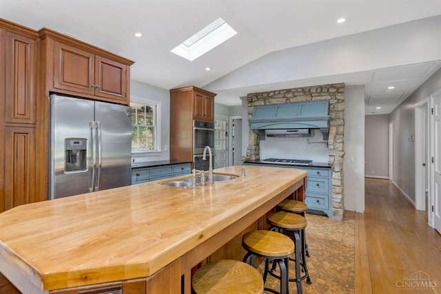 1050 Holz Ave, Anderson Twp, OH 45230 - kitchen featuring appliances with stainless steel finishes, a skylight, vaulted ceiling, wooden counters, and light wood finished floors