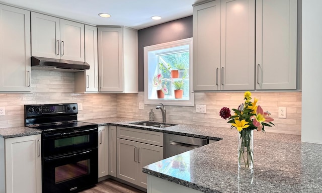 7102 Lookout Ct, Liberty Twp, OH 45011 - kitchen with range with two ovens, under cabinet range hood, dark stone countertops, tasteful backsplash, and recessed lighting