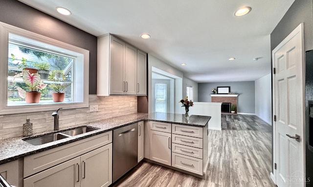 7102 Lookout Ct, Liberty Twp, OH 45011 - kitchen with dishwasher, a peninsula, dark stone countertops, light wood finished floors, and tasteful backsplash