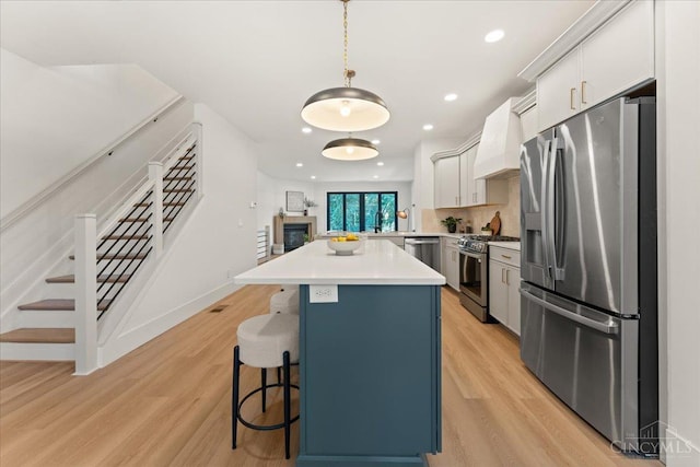 963 Windsor St, Cincinnati, OH 45206 - kitchen featuring stainless steel appliances, custom range hood, a kitchen breakfast bar, light wood-style floors, and recessed lighting