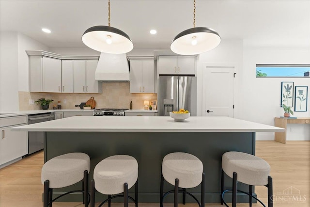 963 Windsor St, Cincinnati, OH 45206 - kitchen featuring stainless steel appliances, custom exhaust hood, a kitchen bar, and recessed lighting