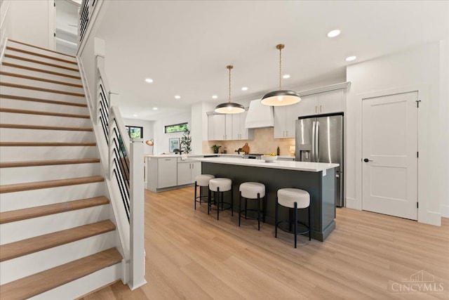 963 Windsor St, Cincinnati, OH 45206 - kitchen featuring light wood-style floors, a kitchen island, a kitchen breakfast bar, custom range hood, and recessed lighting