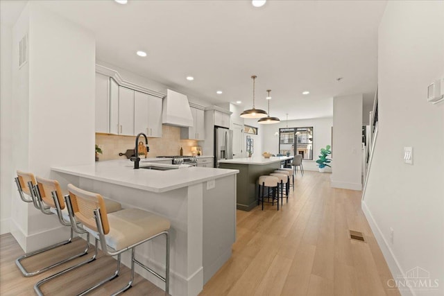 963 Windsor St, Cincinnati, OH 45206 - kitchen featuring stainless steel appliances, a kitchen breakfast bar, premium range hood, recessed lighting, and backsplash