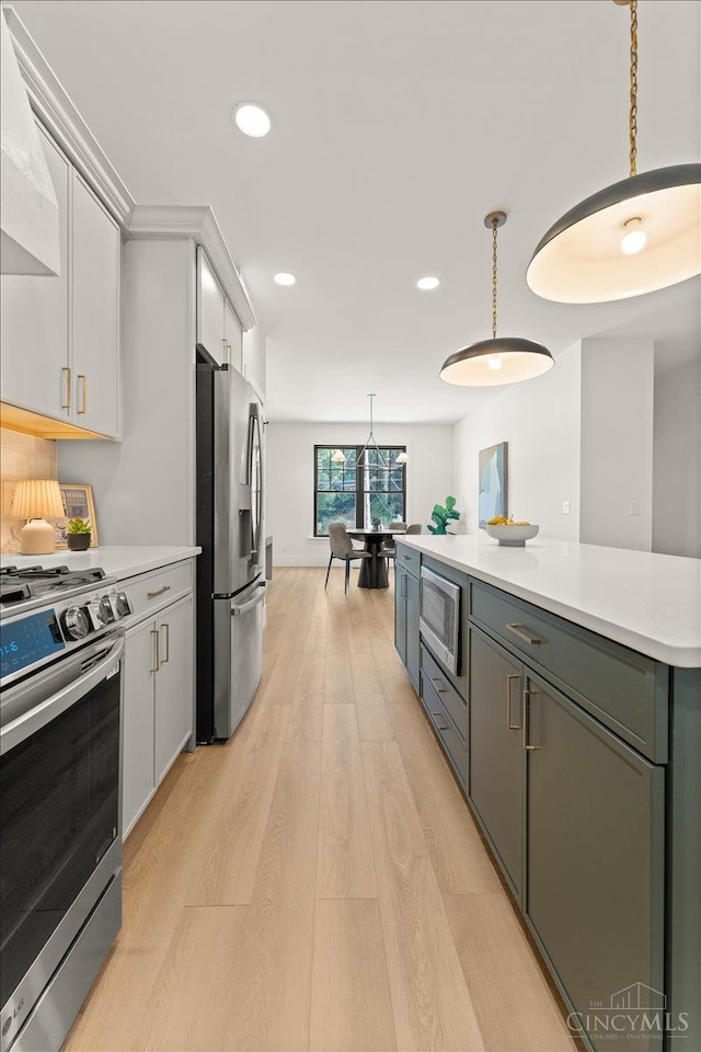 963 Windsor St, Cincinnati, OH 45206 - kitchen with stainless steel appliances, range hood, light wood finished floors, light countertops, and white cabinets