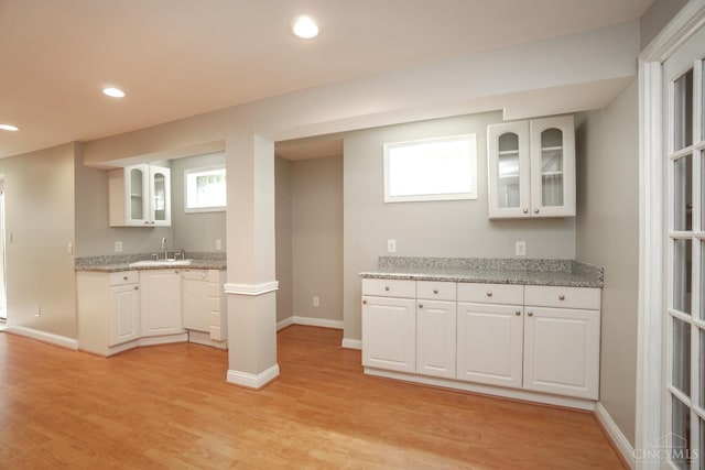 1031 Westchester, Union Twp, OH 45244 - kitchen featuring glass insert cabinets, light wood-type flooring, white cabinetry, recessed lighting, and light stone countertops