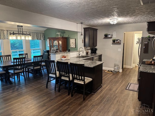 8091 Celestial Cir, Liberty Twp, OH 45044 - kitchen featuring a peninsula, light stone counters, dark wood-style flooring, a breakfast bar, and stainless steel appliances