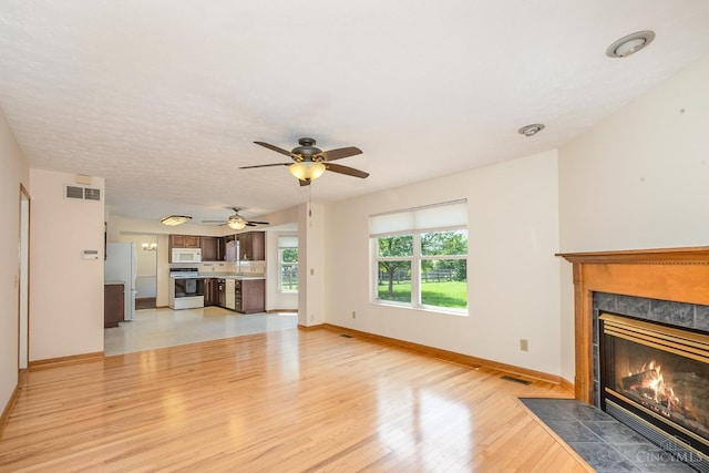 6409 Stapleton Ct, Fairfield Twp, OH 45011 - unfurnished living room with light wood finished floors, a tiled fireplace, and ceiling fan