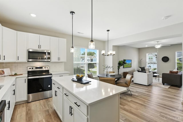 1545 Ruth Ave, Cincinnati, OH 45207 - kitchen with appliances with stainless steel finishes, light wood-style flooring, tasteful backsplash, a center island, and light countertops