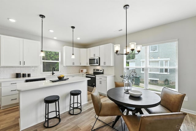 1545 Ruth Ave, Cincinnati, OH 45207 - kitchen with stainless steel appliances, tasteful backsplash, a kitchen bar, a center island, and white cabinets