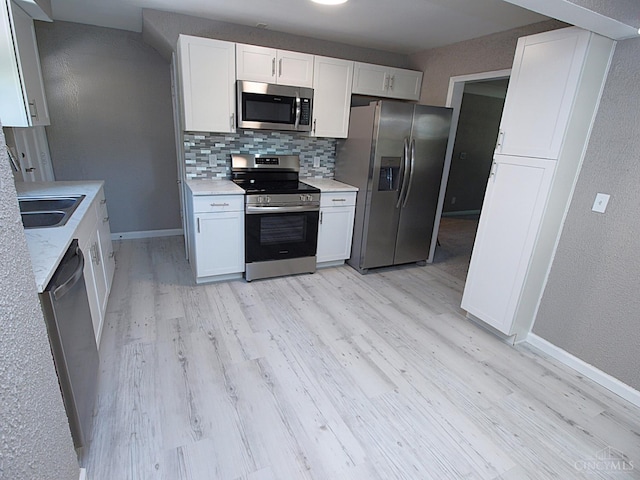 3527 Reemelin Rd, Green Twp, OH 45211 - kitchen with stainless steel appliances, light wood-type flooring, decorative backsplash, white cabinets, and light countertops