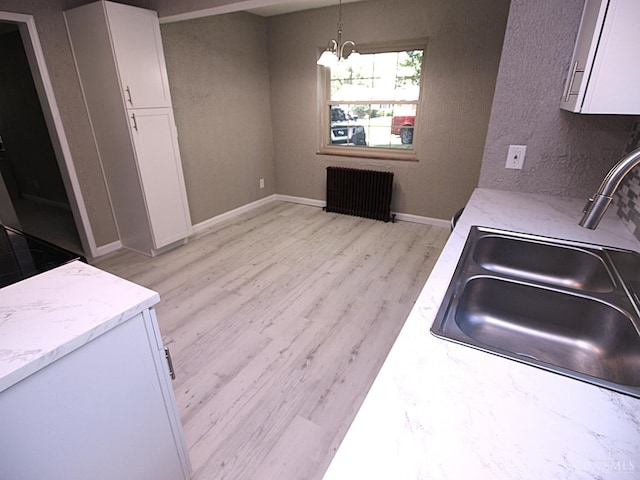 3527 Reemelin Rd, Green Twp, OH 45211 - kitchen with radiator heating unit, white cabinetry, light wood-style floors, and light stone counters