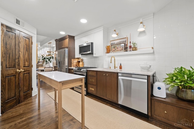 1236 Louden St, Cincinnati, OH 45202 - kitchen featuring appliances with stainless steel finishes, dark wood-style flooring, light countertops, tasteful backsplash, and white cabinetry