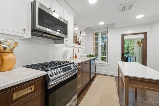 1236 Louden St, Cincinnati, OH 45202 - kitchen with stainless steel appliances, light countertops, dark wood finished floors, white cabinets, and decorative backsplash