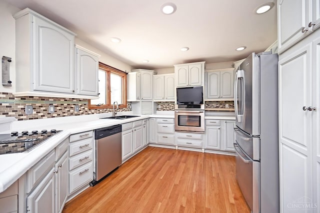 8424 Oak Grove Rd, Georgetown, OH 45121 - kitchen with stainless steel appliances, decorative backsplash, light wood-type flooring, light countertops, and white cabinetry