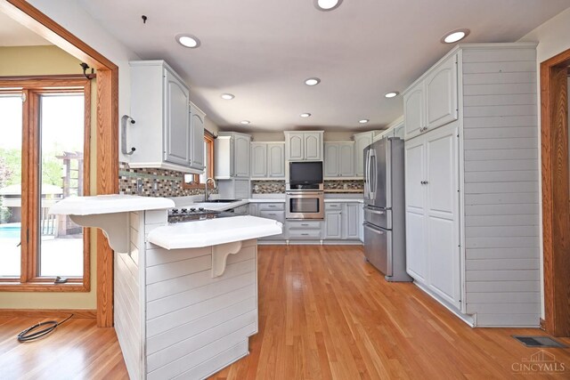8424 Oak Grove Rd, Georgetown, OH 45121 - kitchen featuring freestanding refrigerator, a peninsula, a kitchen bar, tasteful backsplash, and light countertops