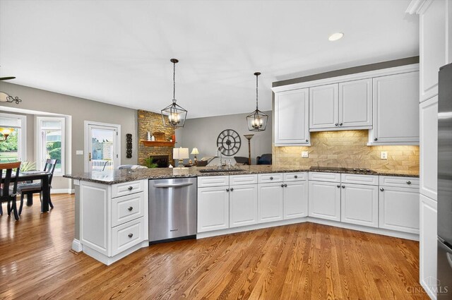 8069 Green Lake Dr, Liberty Twp, OH 45044 - kitchen featuring stainless steel dishwasher, a peninsula, a stone fireplace, light wood finished floors, and white cabinets