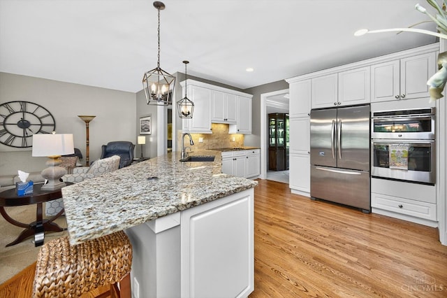 8069 Green Lake Dr, Liberty Twp, OH 45044 - kitchen featuring appliances with stainless steel finishes, a peninsula, white cabinets, light stone countertops, and light wood-style floors