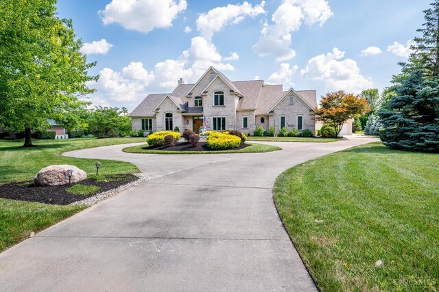 8069 Green Lake Dr, Liberty Twp, OH 45044 - french country style house with stone siding, curved driveway, and a front lawn