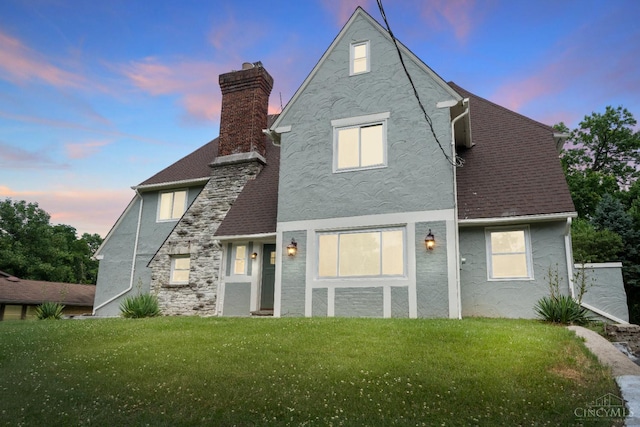4150 Paddock Rd, Cincinnati, OH 45229 - back of property at dusk featuring stucco siding, a yard, and a chimney