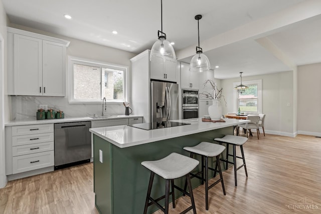 4150 Paddock Rd, Cincinnati, OH 45229 - kitchen with appliances with stainless steel finishes, tasteful backsplash, a kitchen bar, light countertops, and recessed lighting