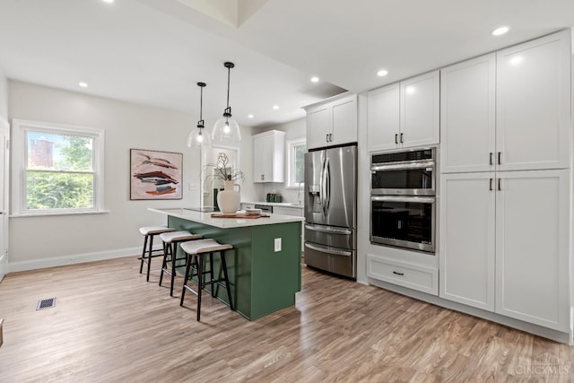 4150 Paddock Rd, Cincinnati, OH 45229 - kitchen featuring appliances with stainless steel finishes, a kitchen island, a breakfast bar, light wood-type flooring, and light countertops