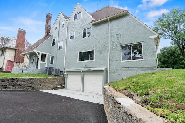 4150 Paddock Rd, Cincinnati, OH 45229 - view of property exterior featuring stucco siding, asphalt driveway, a garage, and a chimney