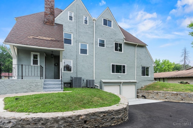 4150 Paddock Rd, Cincinnati, OH 45229 - back of property with a chimney, stucco siding, asphalt driveway, an attached garage, and covered porch