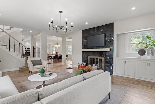 4150 Paddock Rd, Cincinnati, OH 45229 - living room featuring a chandelier, stairway, light wood-style floors, a tile fireplace, and recessed lighting
