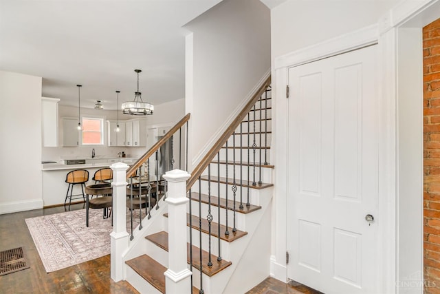 1419 Chase Ave, Cincinnati, OH 45223 - stairway with brick wall, wood finished floors, and a chandelier