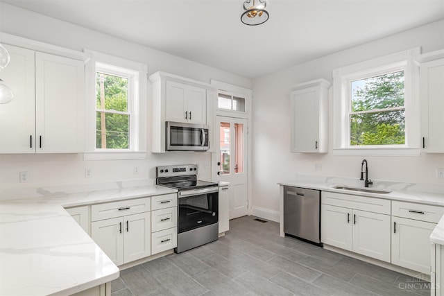1419 Chase Ave, Cincinnati, OH 45223 - kitchen with stainless steel appliances, healthy amount of natural light, light stone counters, and white cabinets