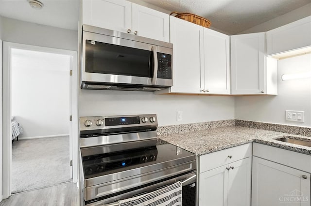 7234 Creekview Dr Unit 1, Colerain Twp, OH 45247 - kitchen with appliances with stainless steel finishes, white cabinets, and light stone countertops