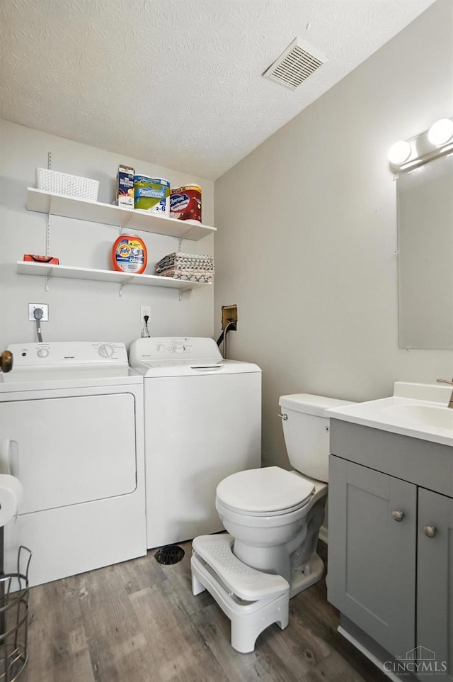 7234 Creekview Dr Unit 1, Colerain Twp, OH 45247 - bathroom featuring washing machine and dryer, wood finished floors, vanity, and a textured ceiling