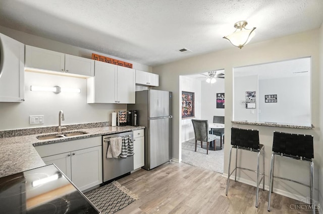 7234 Creekview Dr Unit 1, Colerain Twp, OH 45247 - kitchen with stainless steel appliances, a ceiling fan, light wood-style flooring, white cabinets, and light stone counters