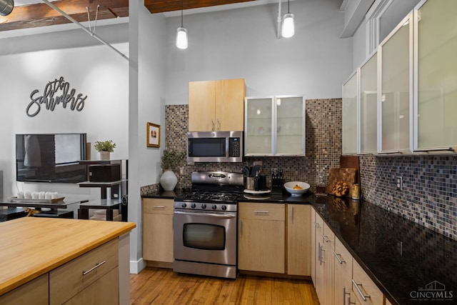 26 E Sixth St Unit 403, Cincinnati, OH 45202 - kitchen featuring stainless steel appliances, backsplash, light wood-style flooring, decorative light fixtures, and a towering ceiling