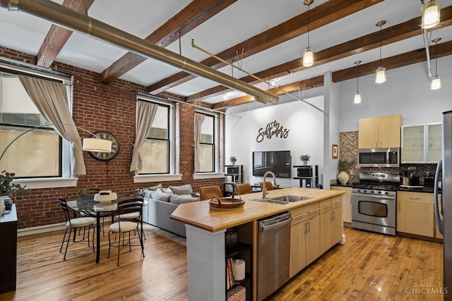 26 E Sixth St Unit 403, Cincinnati, OH 45202 - kitchen featuring appliances with stainless steel finishes, brick wall, light brown cabinetry, wooden counters, and light wood-style flooring