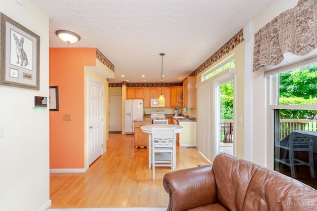 2220 Sulky Ct, Beavercreek Twp, OH 45434 - kitchen with white appliances, light wood finished floors, open floor plan, light countertops, and a center island