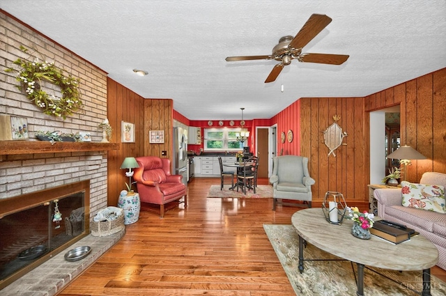 5613 Williamsburg Way, Fairfield, OH 45014 - living area featuring a textured ceiling, light wood finished floors, a ceiling fan, wooden walls, and a fireplace