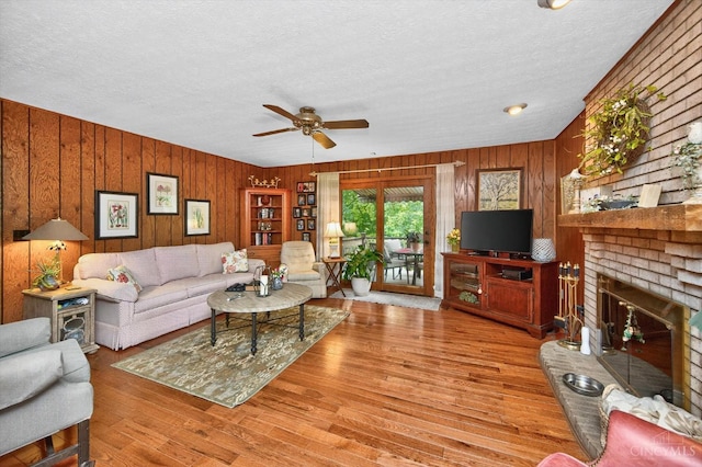 5613 Williamsburg Way, Fairfield, OH 45014 - living room with a textured ceiling, wooden walls, a ceiling fan, a brick fireplace, and wood finished floors