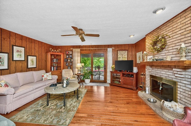 5613 Williamsburg Way, Fairfield, OH 45014 - living area featuring wood walls, a textured ceiling, ceiling fan, wood finished floors, and a brick fireplace