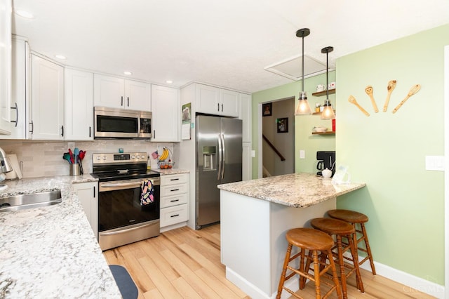 8558 High Trail Ct, Deerfield Twp, OH 45040 - kitchen featuring stainless steel appliances, light wood-style flooring, white cabinets, backsplash, and a kitchen bar