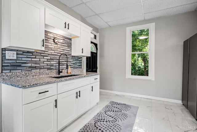 3997 Washington Ave, Cheviot, OH 45211 - kitchen with light marble finish flooring, light stone countertops, white cabinetry, decorative backsplash, and a drop ceiling