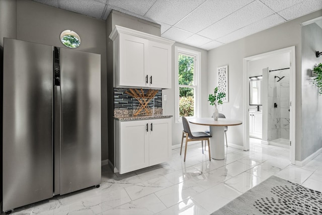 3997 Washington Ave, Cheviot, OH 45211 - kitchen with freestanding refrigerator, white cabinetry, tasteful backsplash, a drop ceiling, and light marble finish floors