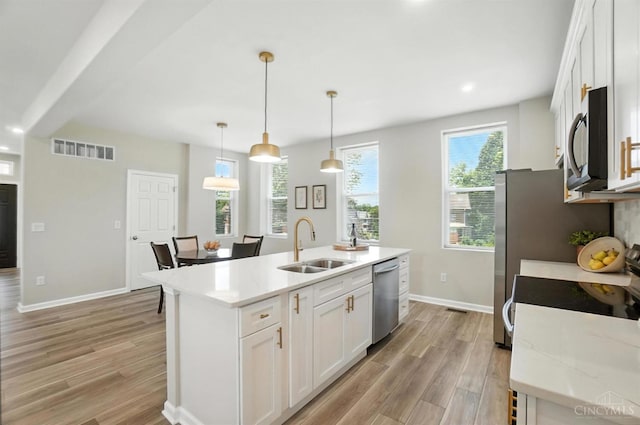 1582 Dixmont Ave, Cincinnati, OH 45207 - kitchen with appliances with stainless steel finishes, light wood-style flooring, an island with sink, white cabinets, and recessed lighting