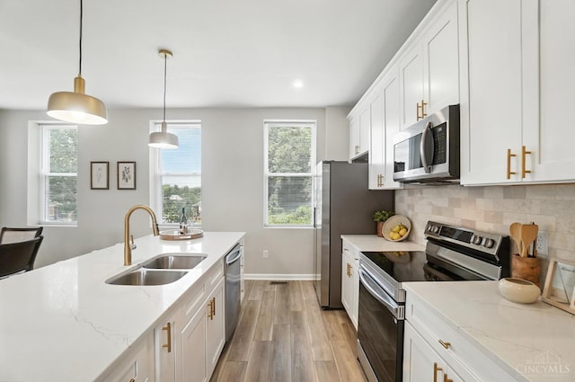 1582 Dixmont Ave, Cincinnati, OH 45207 - kitchen with appliances with stainless steel finishes, light wood finished floors, white cabinetry, decorative backsplash, and hanging light fixtures