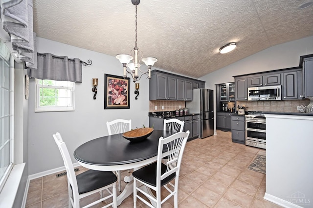 4154 Fieldsedge Dr, Mason, OH 45040 - dining area featuring a chandelier, vaulted ceiling, a textured ceiling, and light tile patterned floors