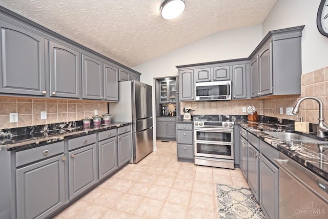 4154 Fieldsedge Dr, Mason, OH 45040 - kitchen with stainless steel appliances, gray cabinets, lofted ceiling, backsplash, and a textured ceiling