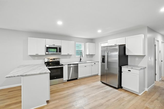 152 N College St, Sabina, OH 45169 - kitchen with stainless steel appliances, a peninsula, white cabinetry, light wood-style floors, and light stone counters